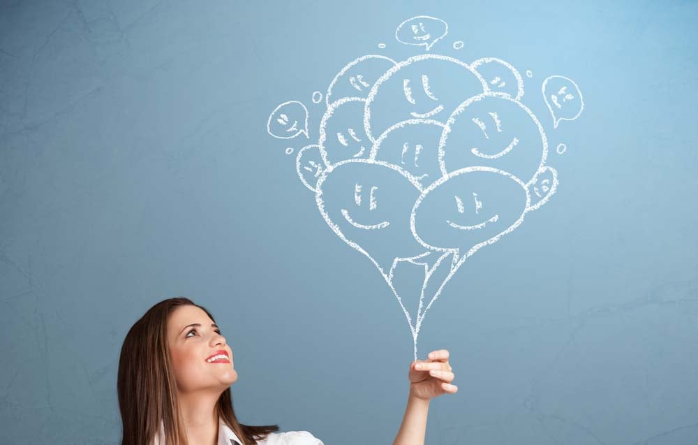 Happy young woman holding smiling balloons drawing
