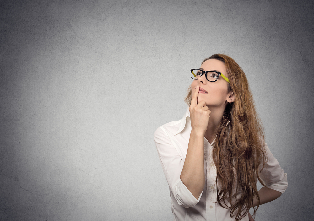 Portrait happy beautiful woman thinking looking up isolated grey wall background with copy space. Human face expressions, emotions, feelings, body language, perception