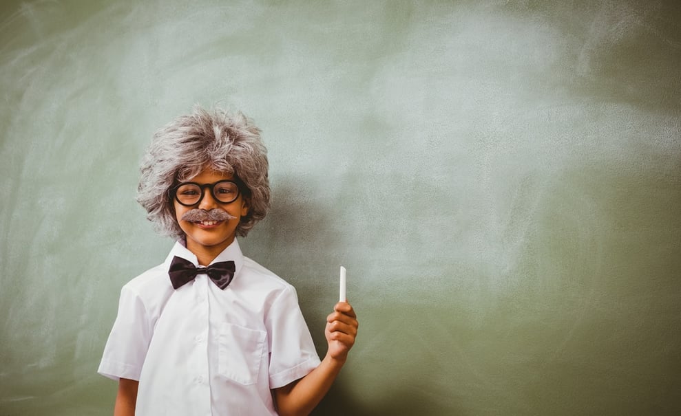 Portrait of little boy dressed as senior teacher in front of blackboard.jpeg