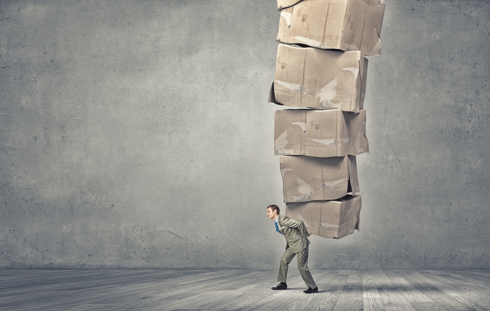 Young businessman in suit carrying big stack of carton boxes